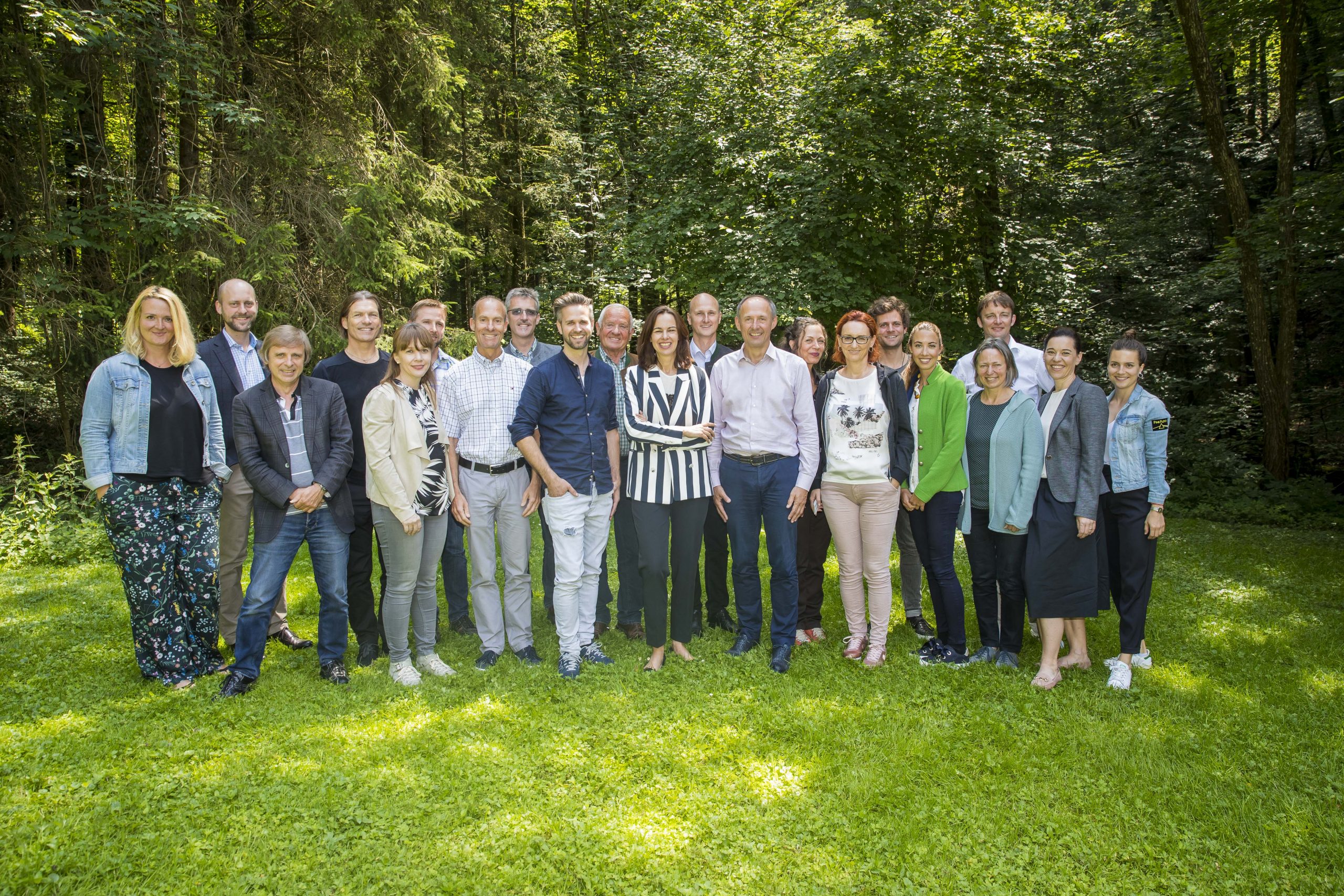 Eine Gruppe von Menschen steht zusammen und lächelt in einem üppigen, grünen Wald.
