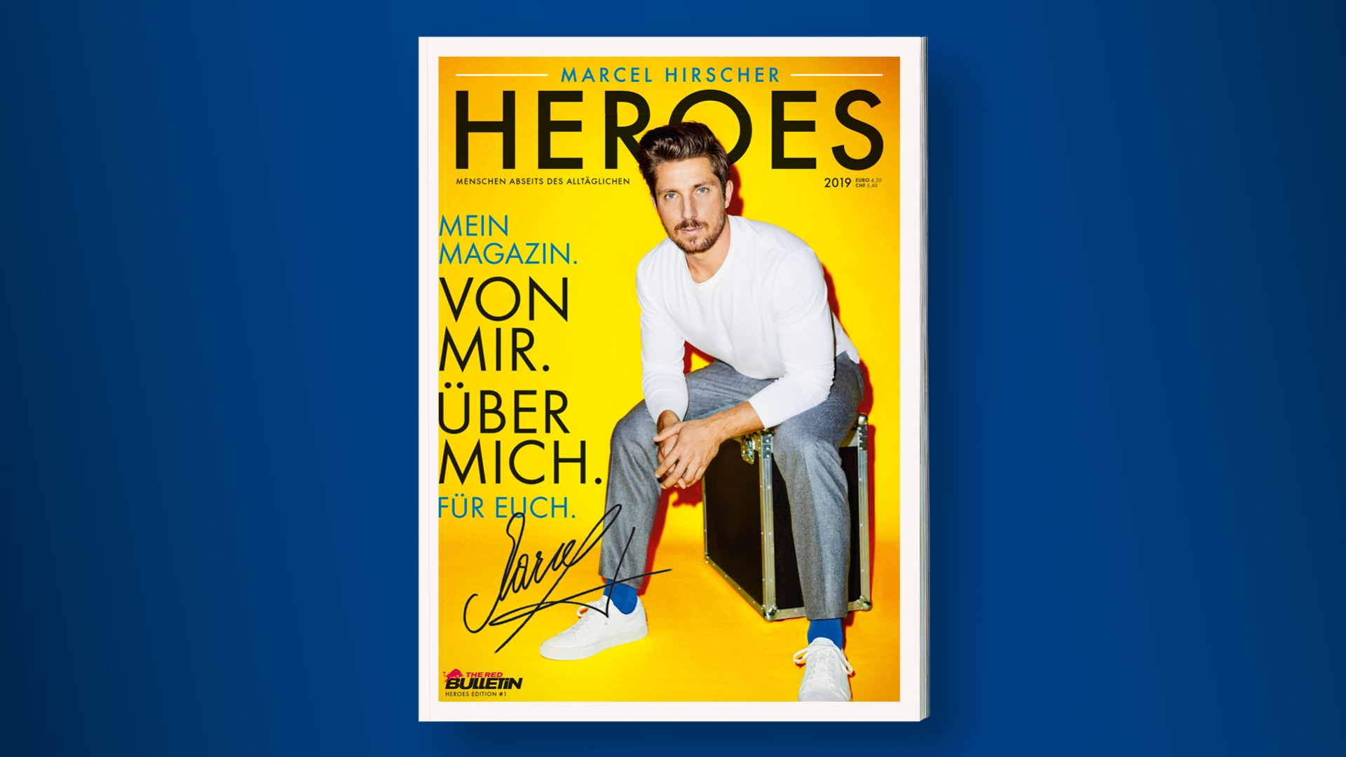 Ein Mann in einem weißen Hemd und einer grauen Hose sitzt auf einer Kiste vor einem gelben Hintergrund auf einem Zeitschriftencover.