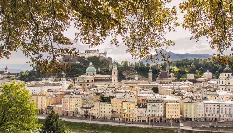 Blick auf Salzburgs historisches Stadtbild mit Festung, Fluss und grünen Zweigen - weit entfernt von der Skyline Asiens.