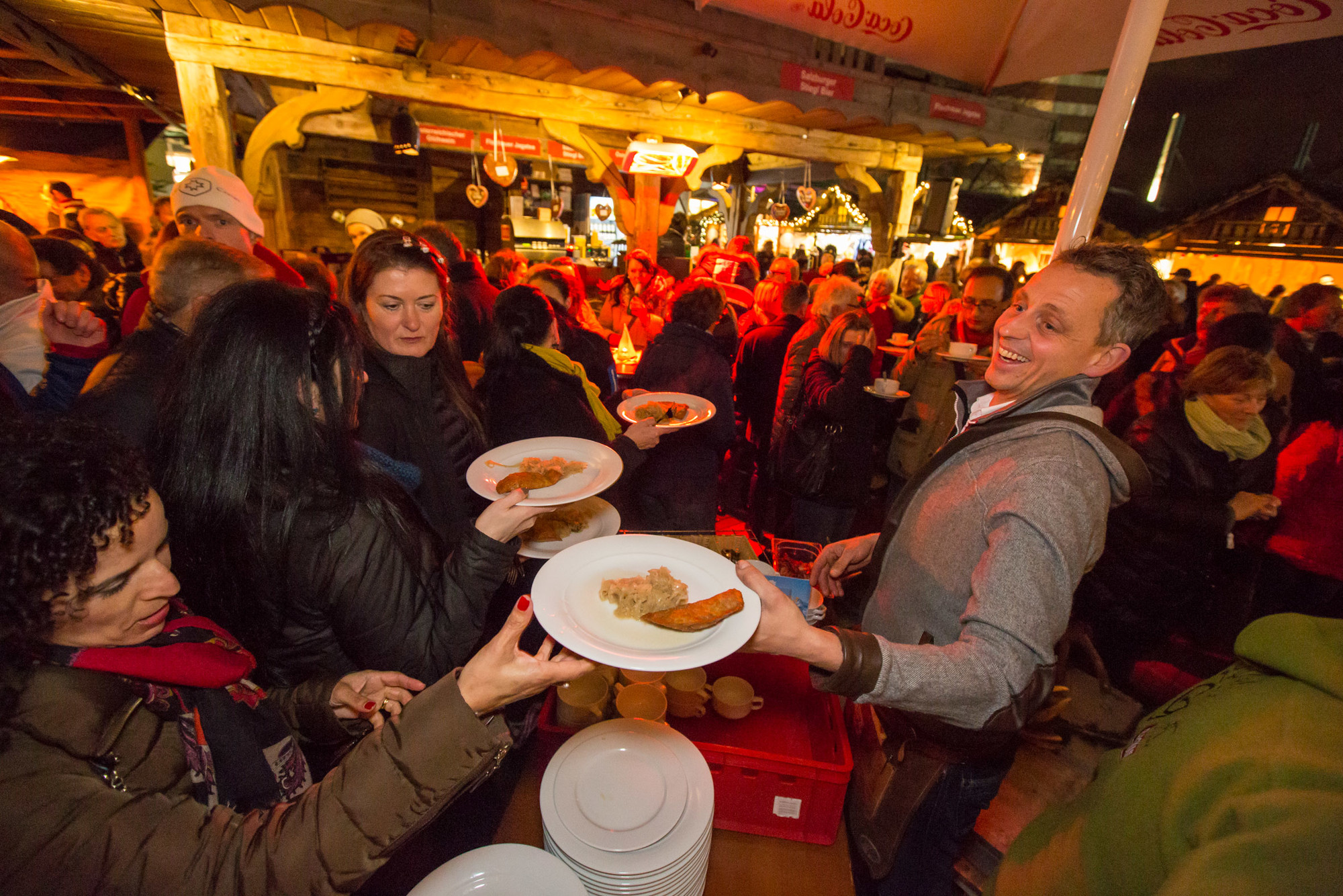 Menschen versammeln sich an einem belebten Essensstand und nehmen auf einem lebhaften Nachtmarkt im Freien Teller mit Essen entgegen.