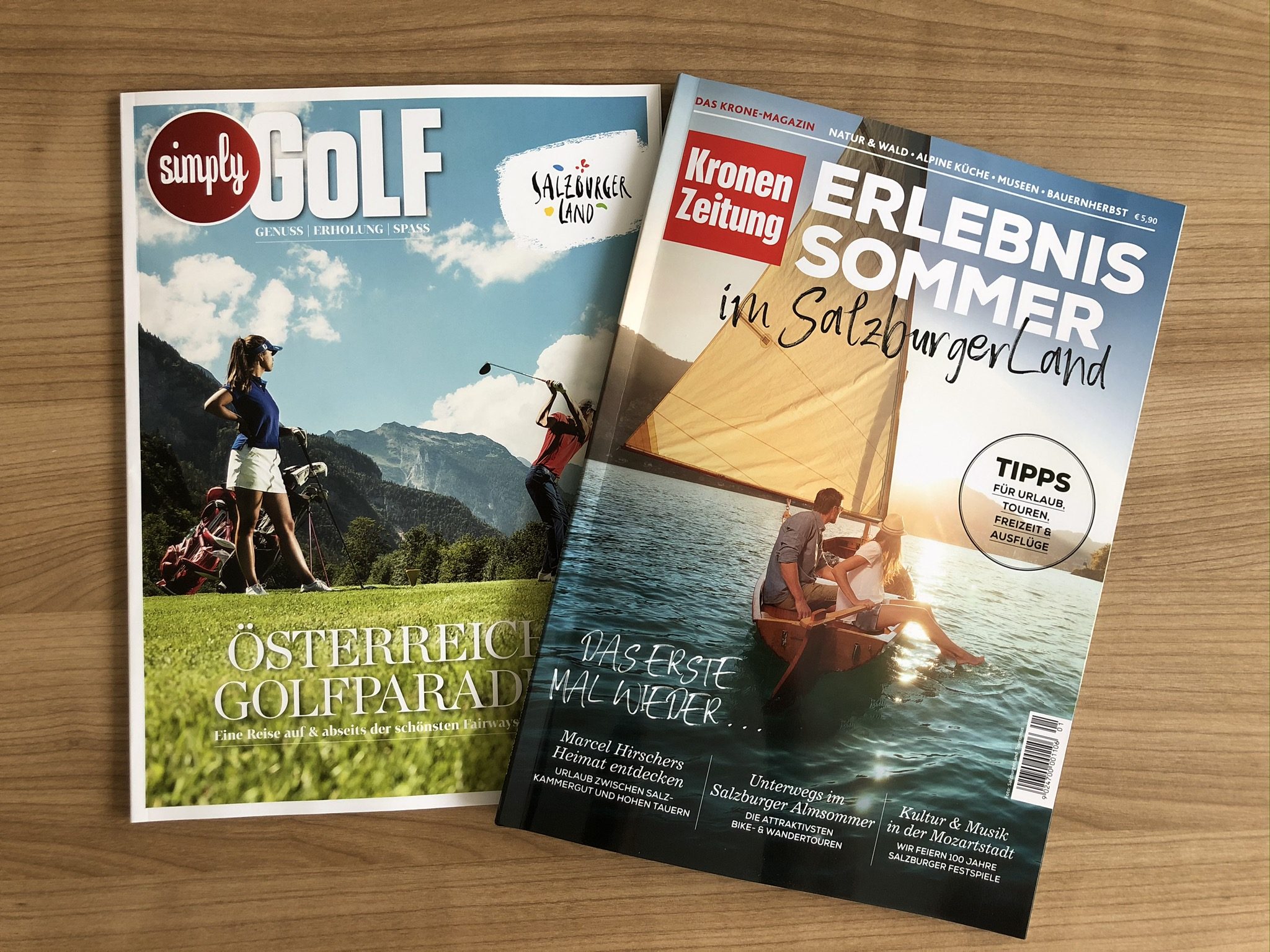 Zwei Zeitschriften auf einem Tisch: eine über Golf in Österreich, die andere über Sommererlebnisse im Salzburger Land.