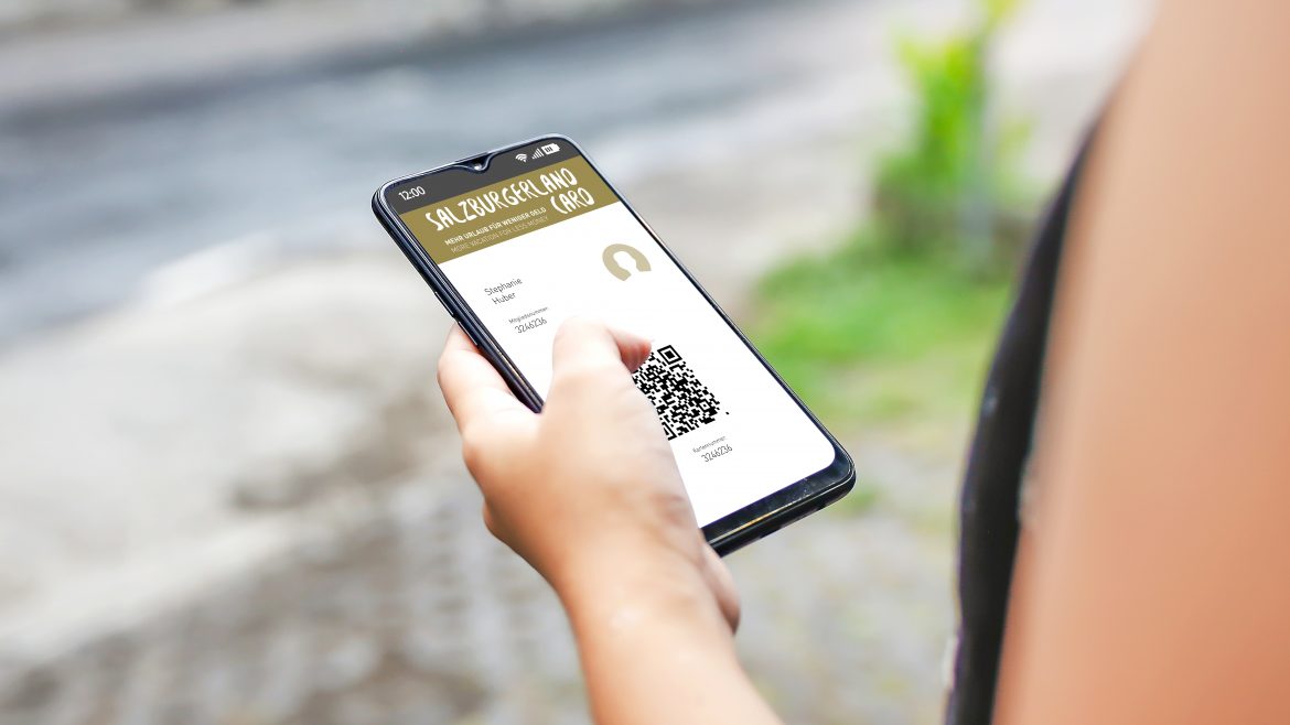 Eine Person hält ein Smartphone in der Hand und zeigt eine digitale Mitgliedskarte mit einem QR-Code im Freien.