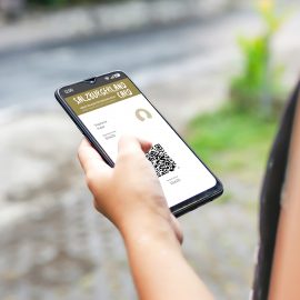 Eine Person hält ein Smartphone in der Hand und zeigt eine digitale Mitgliedskarte mit einem QR-Code im Freien.