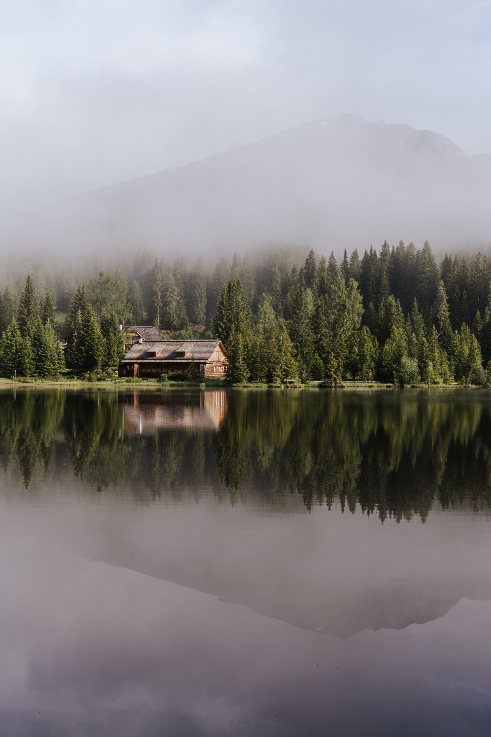 Bergsee in Nebelstimmung, am See spiegelt sich die Hütte